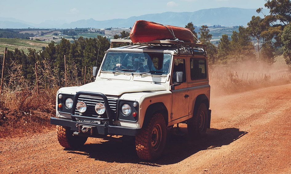 A nursery with green, striped walls, white curtains, and white and black photo frames on the wall. There’s an orange chair with a stuffed toy in it and a small laundry basket to the left. On the right there is a black crib with a white canopy over it, a black changing table with items on top, and a black shelf on the wall above it with photo frames on it. A white wooden rocking horse is in front of the changing table. The text A Nursery is written beneath it on a mint green background. 