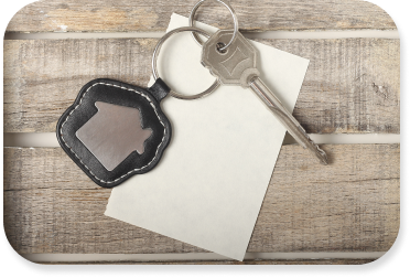 A single key sits on top of a piece of paper with a keychain that has the logo of a home.